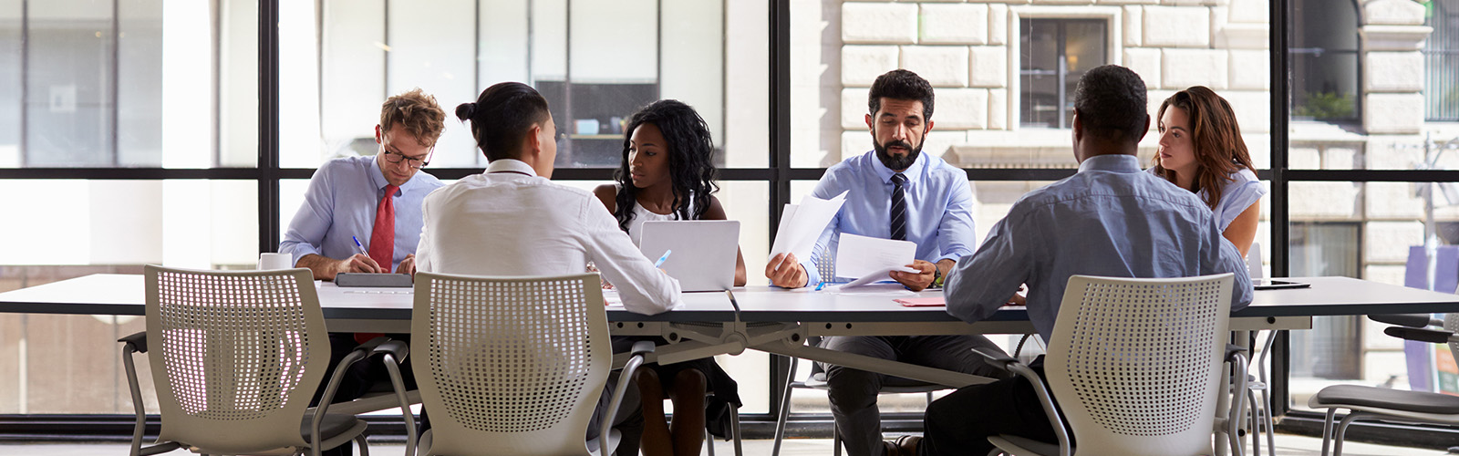 A team meeting with professionals, backdrop of buildings through glass windows