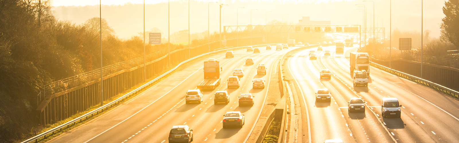 Image of a UK highway with cars travelling at sunset