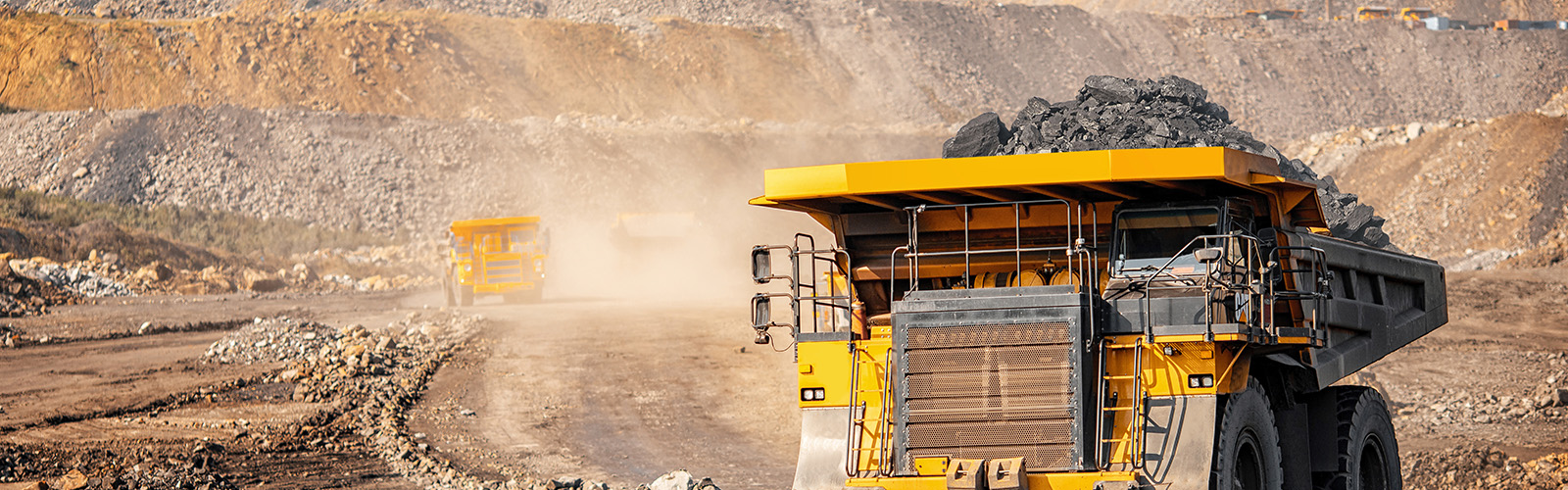 Giant yellow truck carrying materials, on a road in a quarry